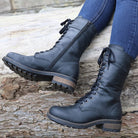 Model walking in black Bridge 12 military boots on a gravel surface