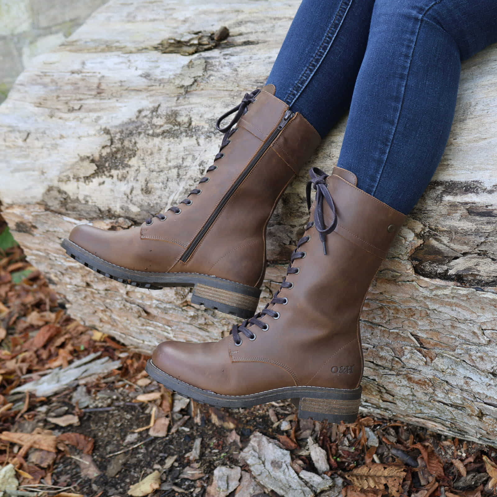 Dark brown Bridge 12 military boots worn outdoors while seated on a stone surface