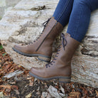 Dark brown Bridge 12 military boots worn outdoors while seated on a stone surface