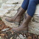 Dark brown Bridge 12 military boots worn outdoors while seated on a stone surface