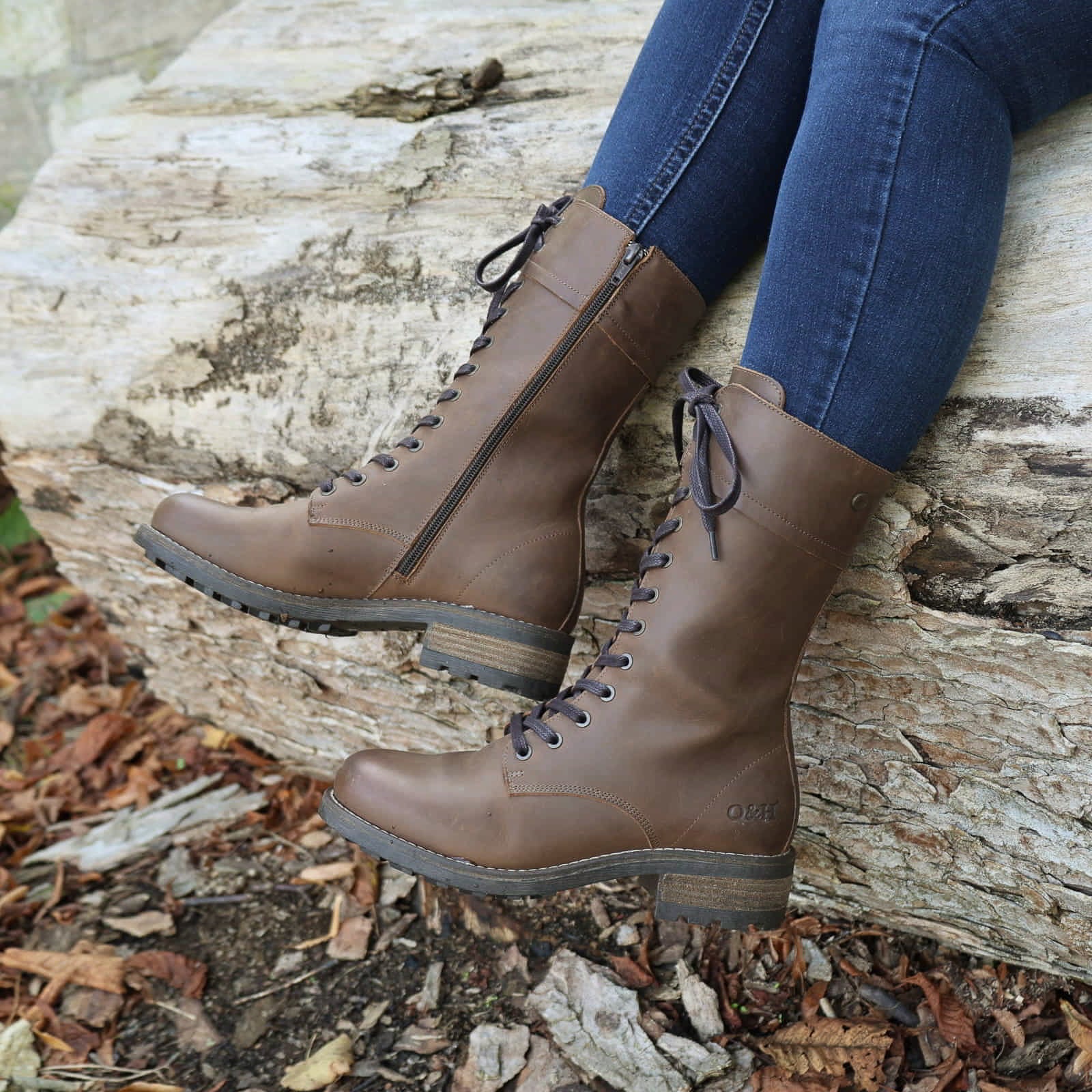 Dark brown Bridge 12 military boots worn outdoors while seated on a stone surface