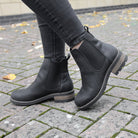 model wearing black bridge chelsea boots with dark jeans on pavement