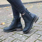 model wearig black bridge chelsea boots with dark jeans on pavement