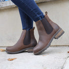Dark brown Bridge Chelsea 2 boots worn with jeans walking beside a stone wall