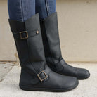 model wearing cedar barefoot boots in black standing on concrete showing buckles