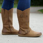 person standing on path in tan barefoot boots with blue jeans