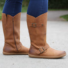 person standing on path in tan barefoot boots with blue jeans