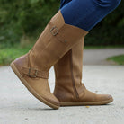 person wearing tan boots with blue jeans on outdoor path