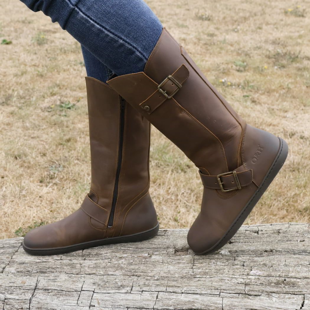 model standing outdoors wearing cedar barefoot boots in brown with blue jeans
