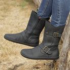 person sitting outdoors wearing cedar demi barefoot boots in black with blue jeans