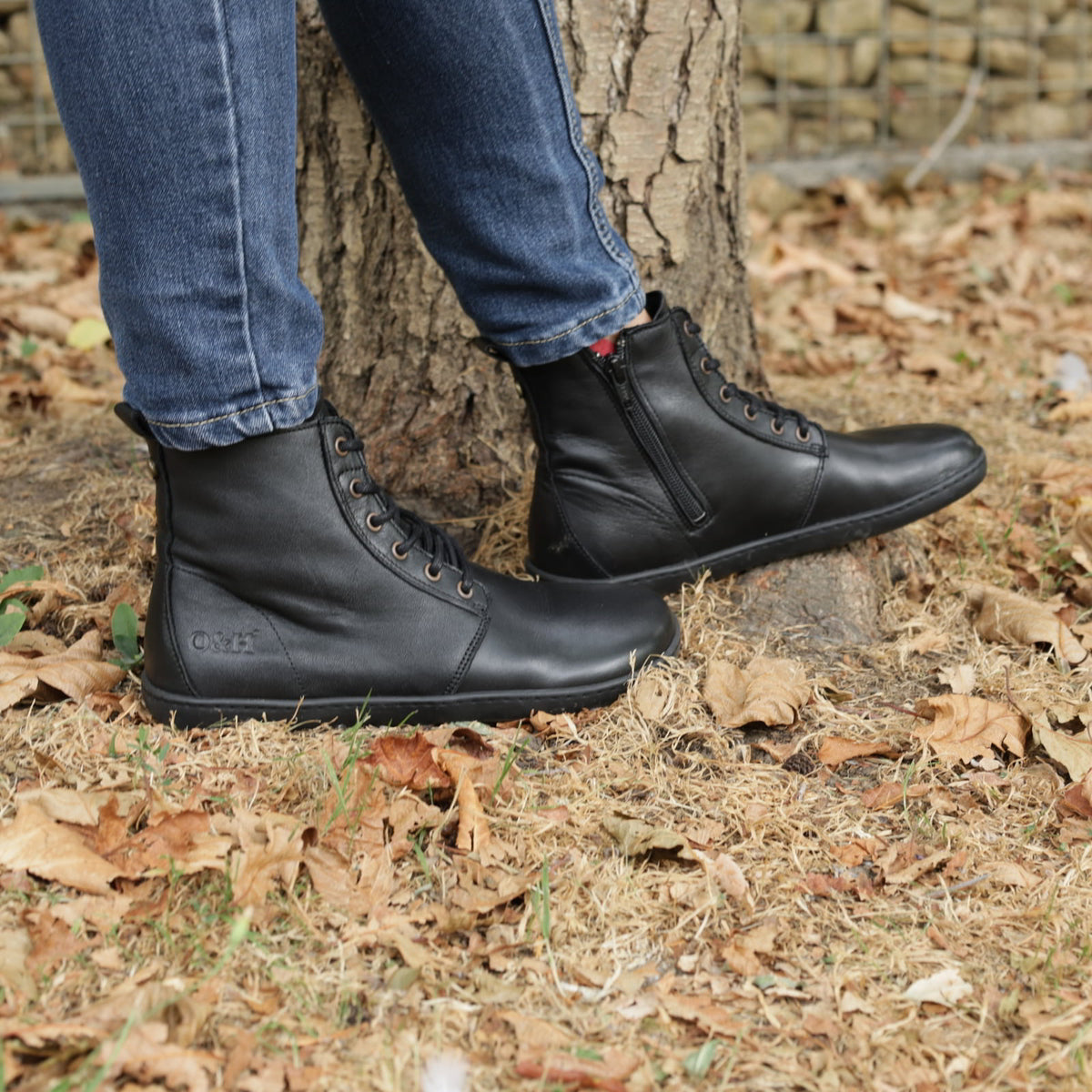 person wearing womens cherry barefoot ankle boots in black outdoors standing in leaves