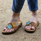 model standing outdoors wearing clover sandals in tan with blue jeans