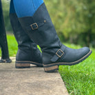 Black Crest 2 wide calf tall boots worn outdoors sitting on a bench