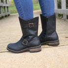 Black Crest Demi 2 ankle boots worn outdoors standing on a wooden walkway