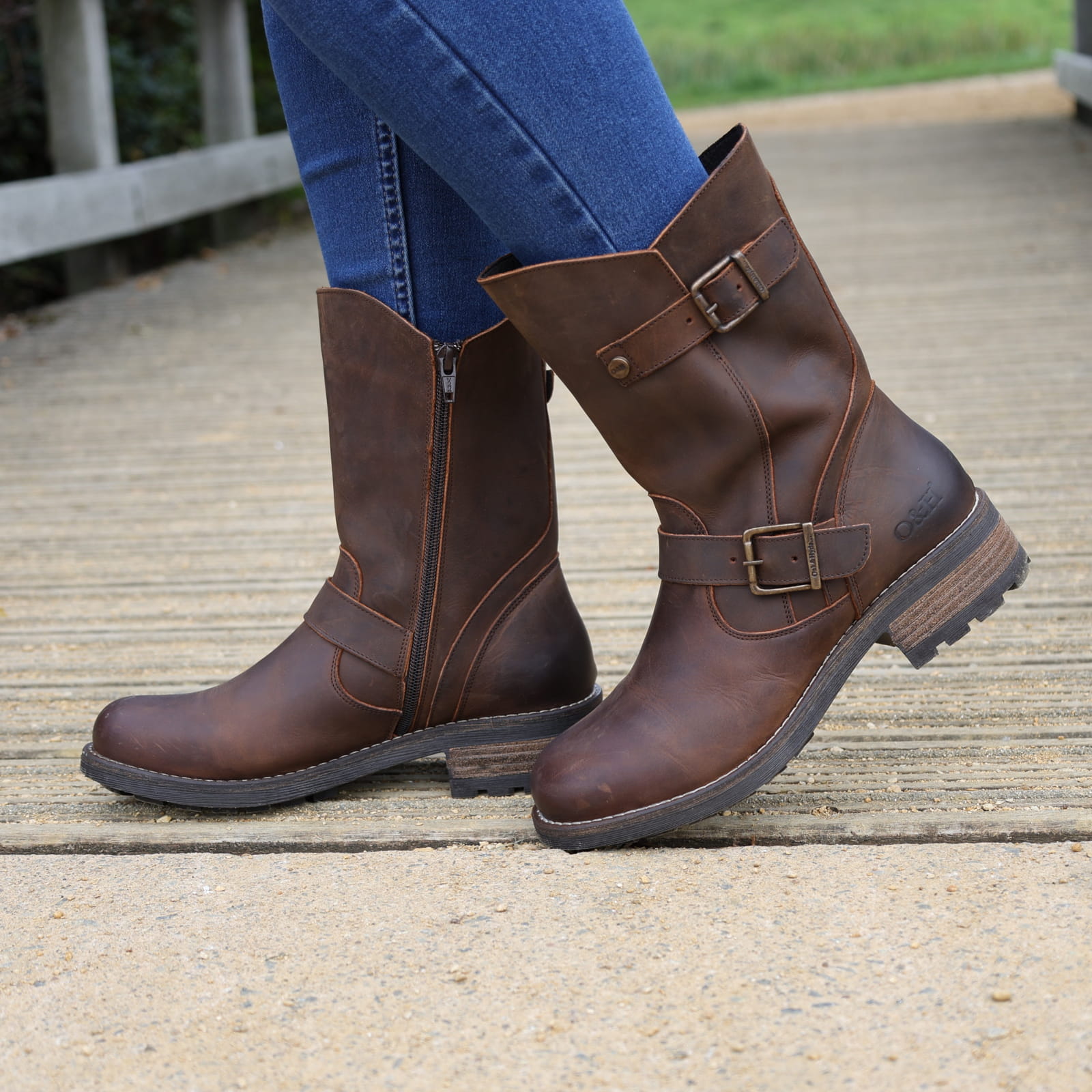 Dark brown Crest Demi 2 ankle boots worn outdoors with jeans on a wooden walkway