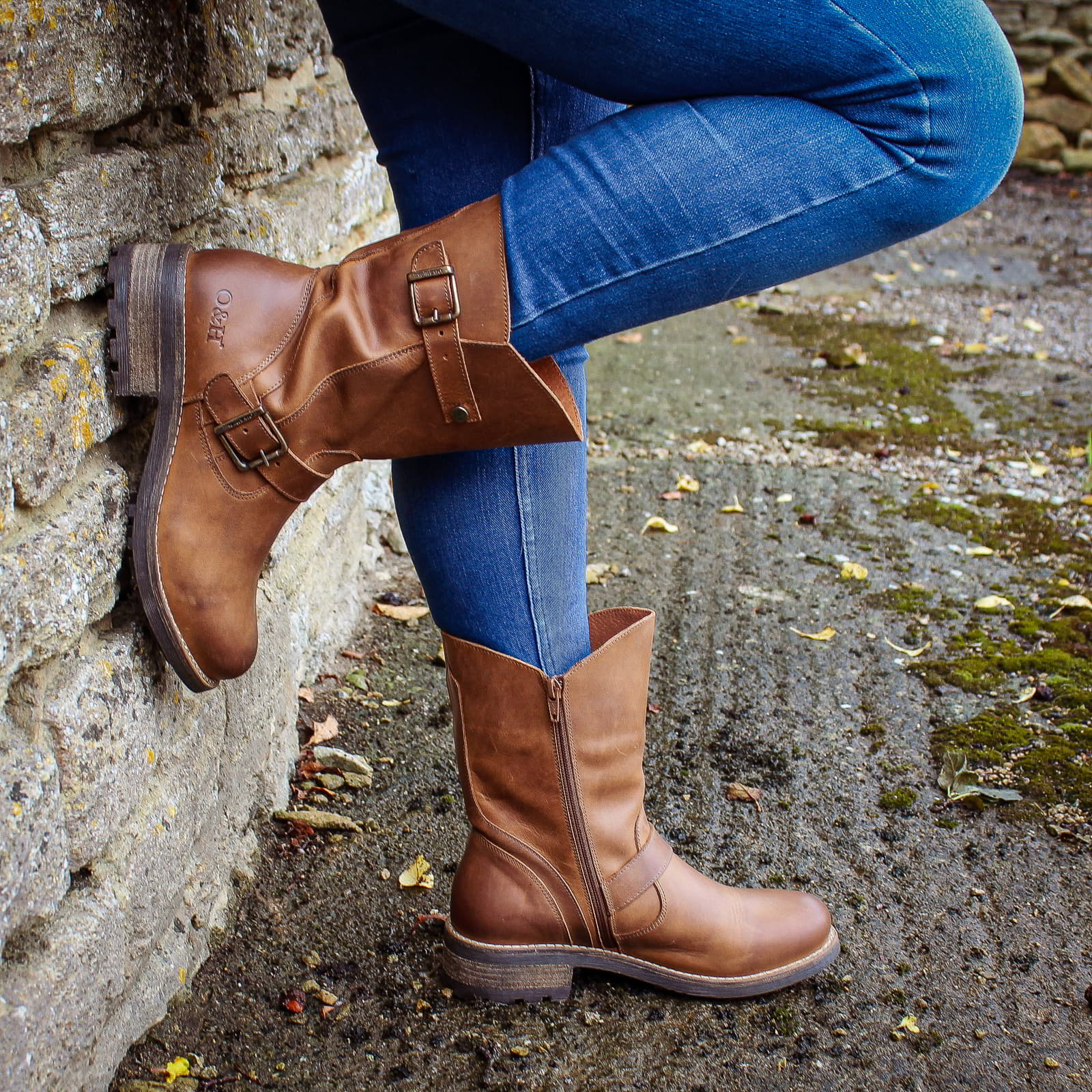 Cognac Crest Demi 2 ankle boots worn with jeans beside a stone wall outdoors