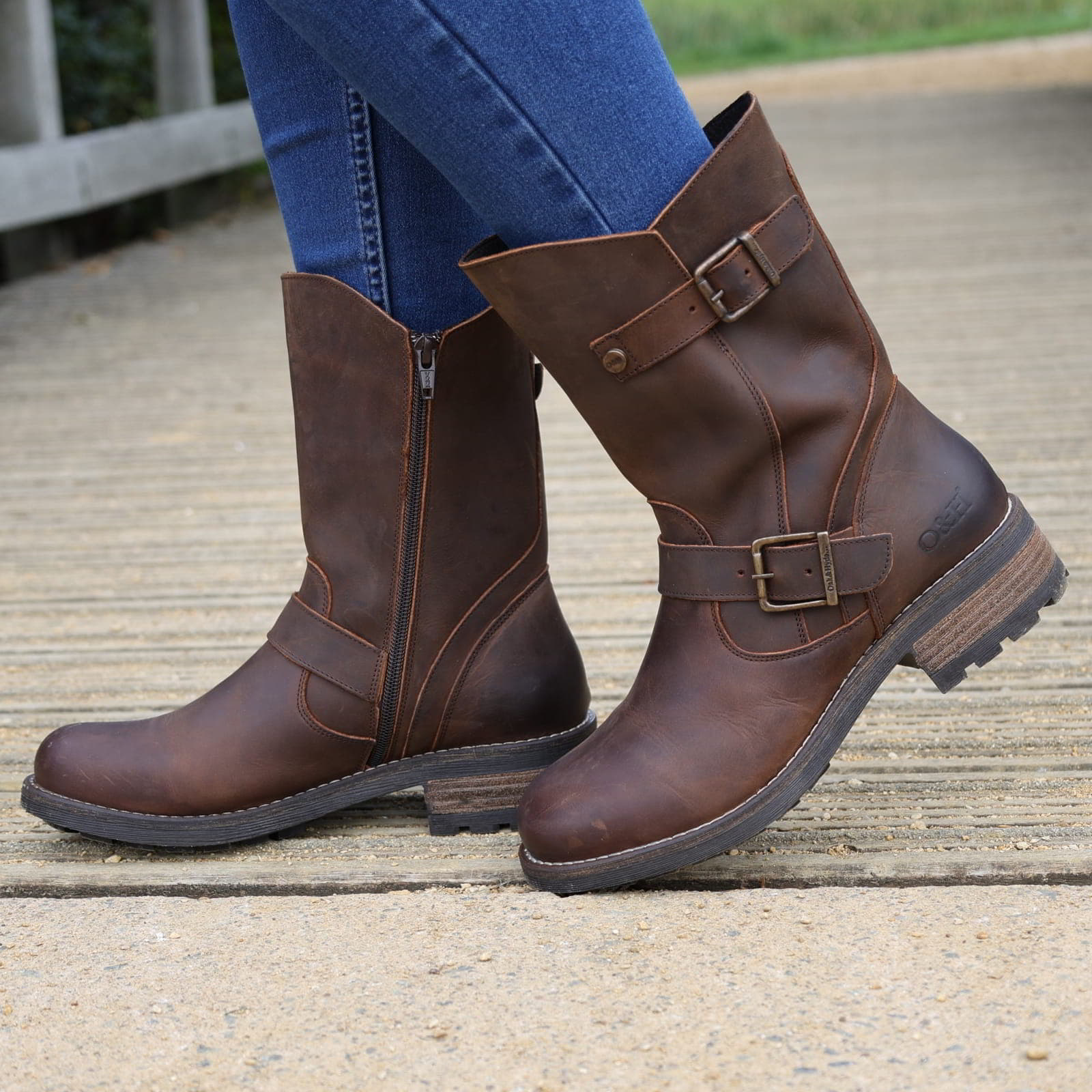 Dark brown Crest Demi 2 ankle boots worn outdoors with jeans on a wooden walkway