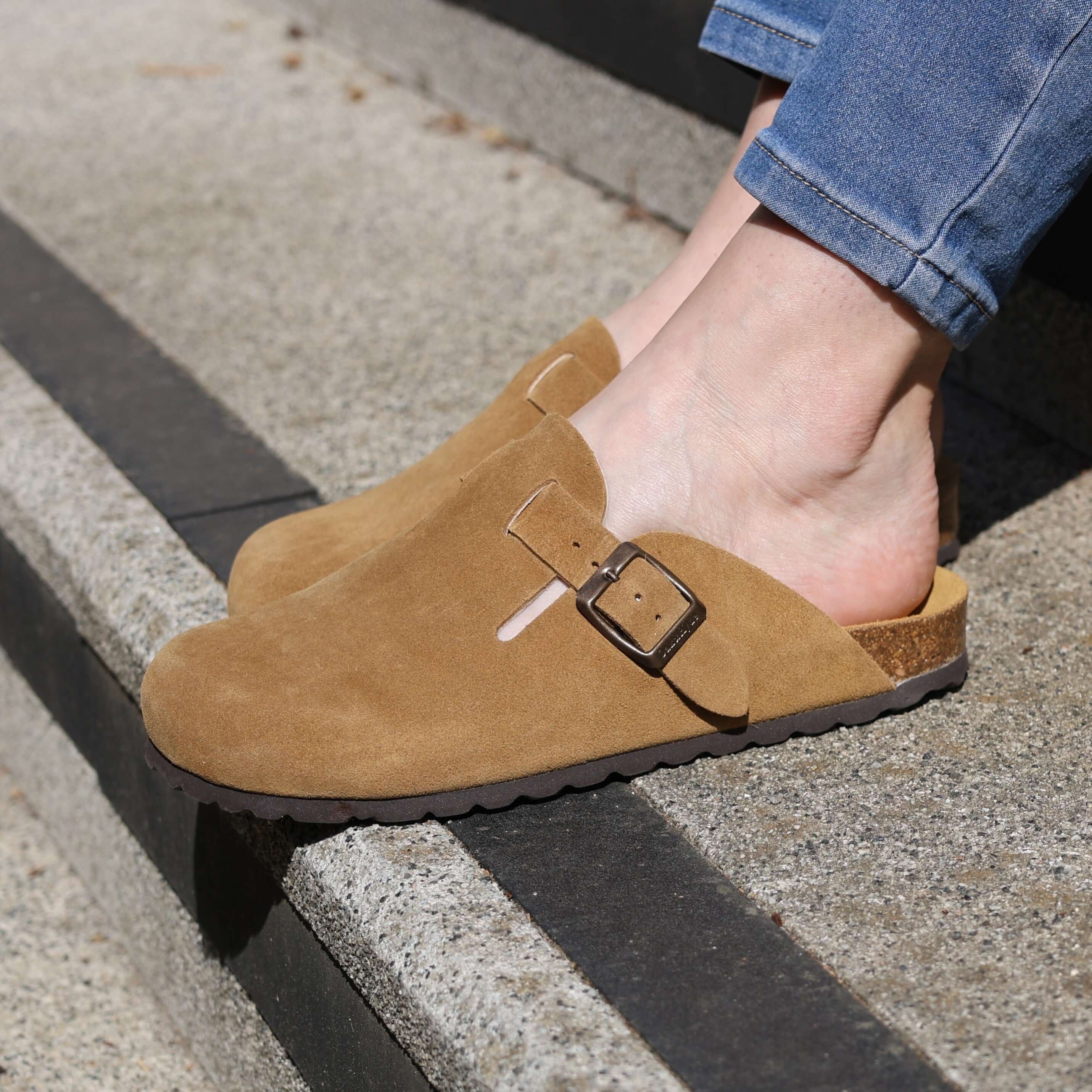 model sat on steps wearing tan gibraltar clogs with blue jeans
