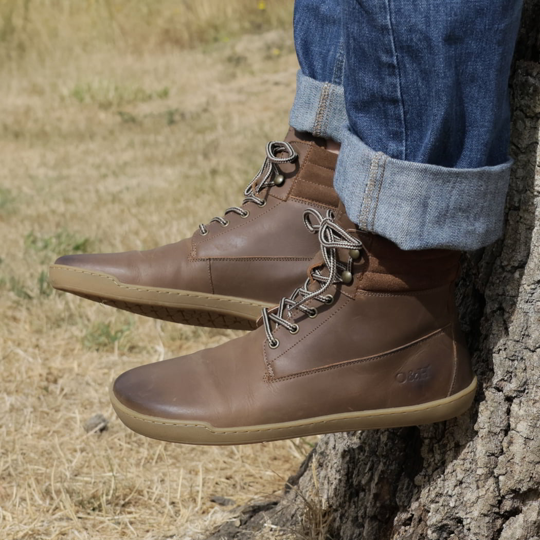 model sitting on tree stump wearing hawthorn mens barefoot boots in brown