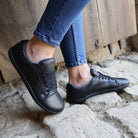 model wearing jeans with black barefoot trainers standing on stone paving