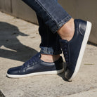 model standing outdoors wearing womens hazel navy barefoot trainers with jeans