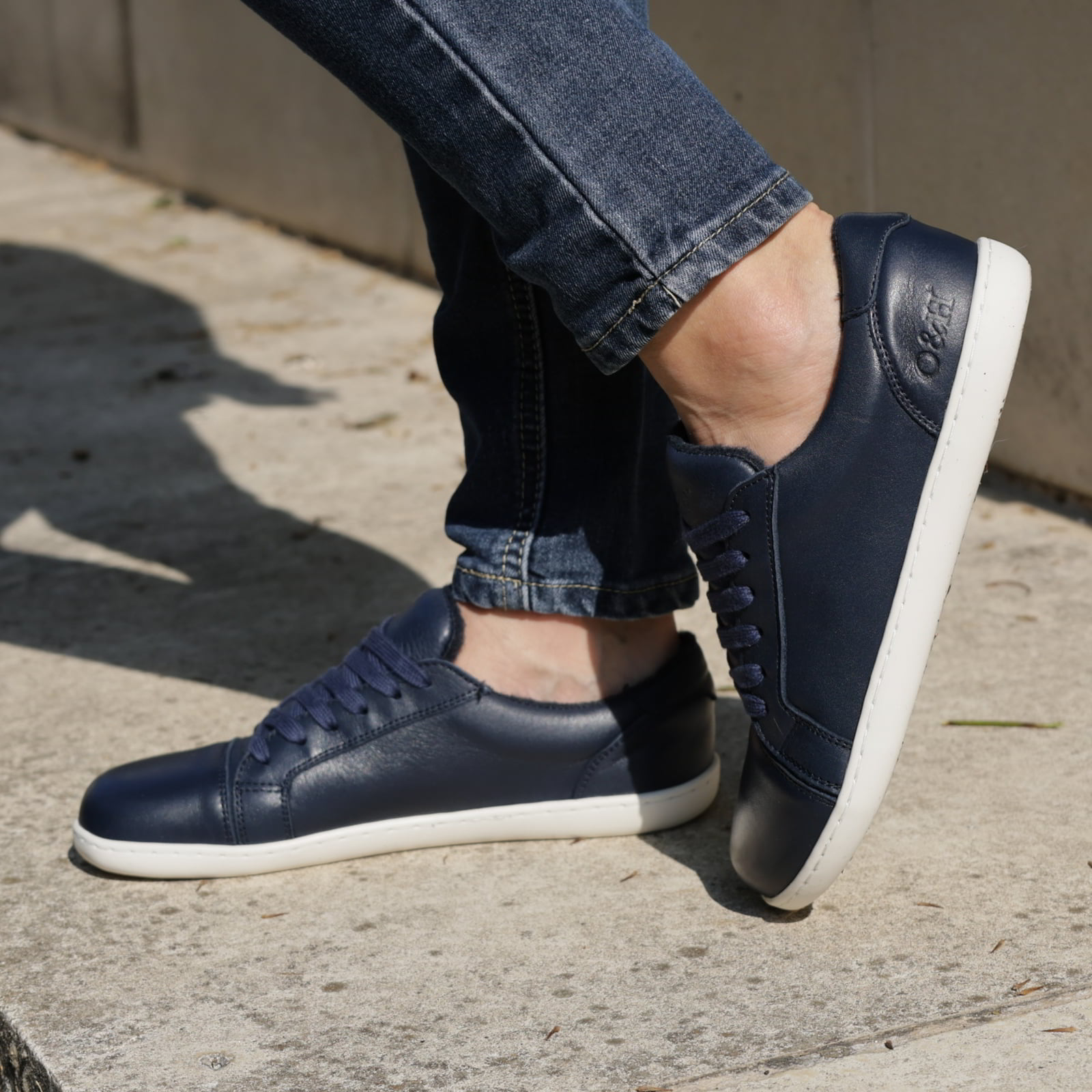 model standing outdoors wearing womens hazel navy barefoot trainers with jeans
