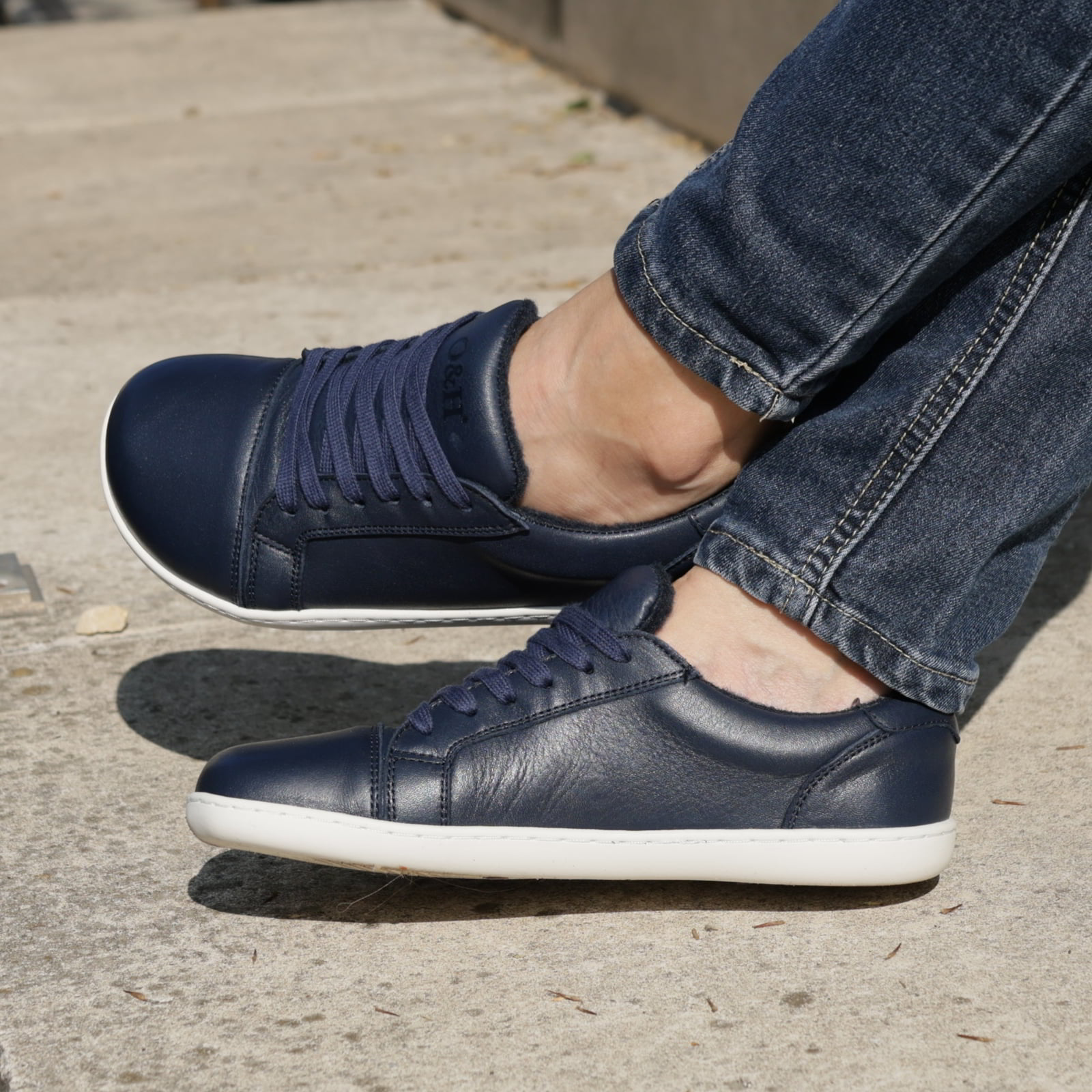model sitting outdoors wearing hazel womens barefoot trainers in navy