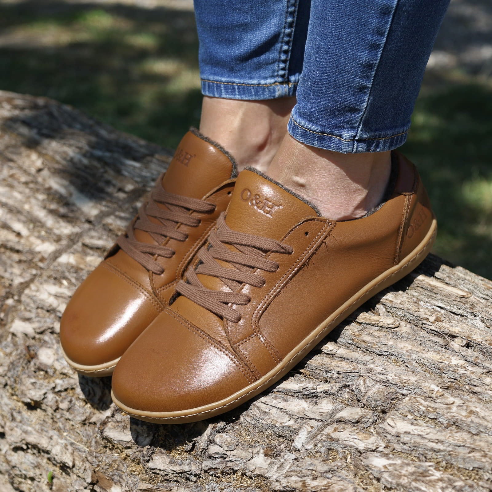 model wearing tan brown barefoot trainers stood on a log with jeans on