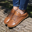 model wearing tan brown barefoot trainers stood on a log with jeans on