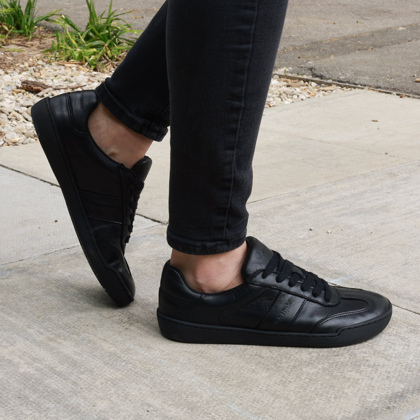 model wearing juniper all black barefoot trainers with dark jeans on a pavement