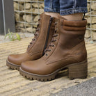 model standing outdoors wearing kensington 2 lace up boots in brown on pavement