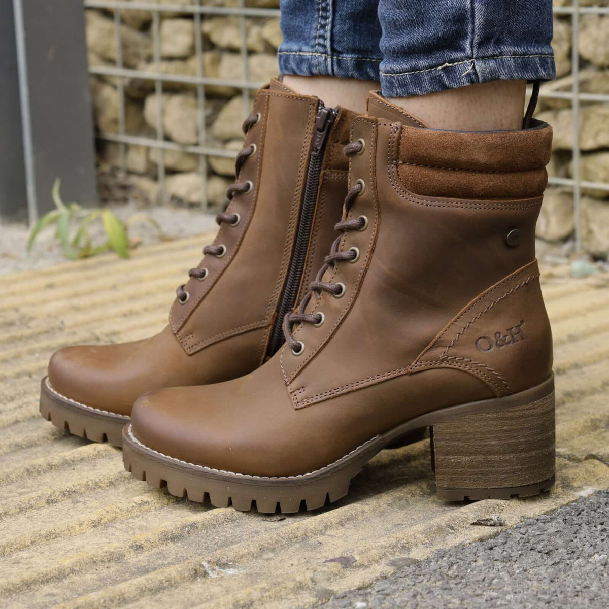 model standing outdoors wearing kensington 2 lace up boots in brown on pavement