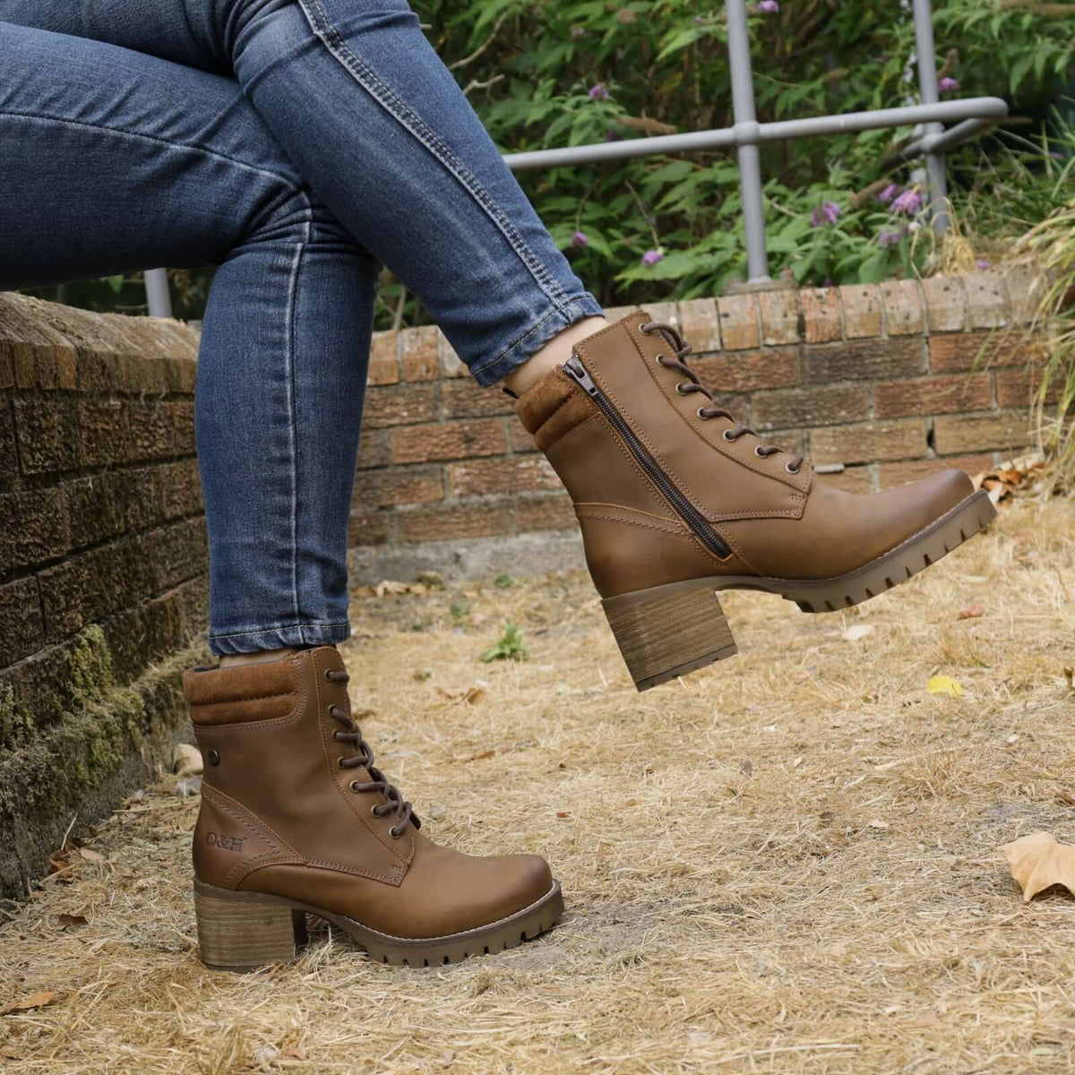 model sitting on wall outdoors wearing kensington 2 lace up boots with crossed legs