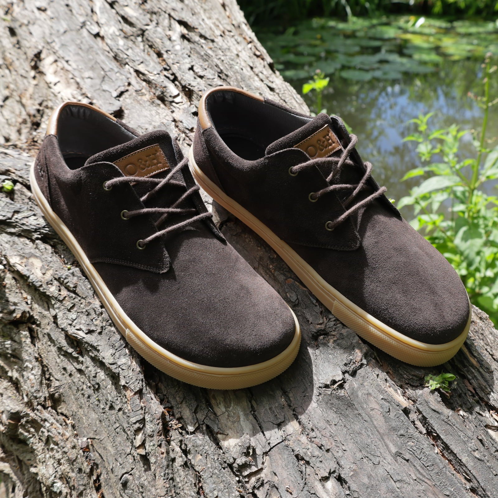 pair of lawson barefoot shoes in dark brown outside on a tree trunk showing branding on tongue