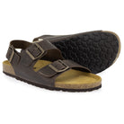 Pair of dark brown leather fisherman sandals, one showing the patterned black rubber sole and cork footbed