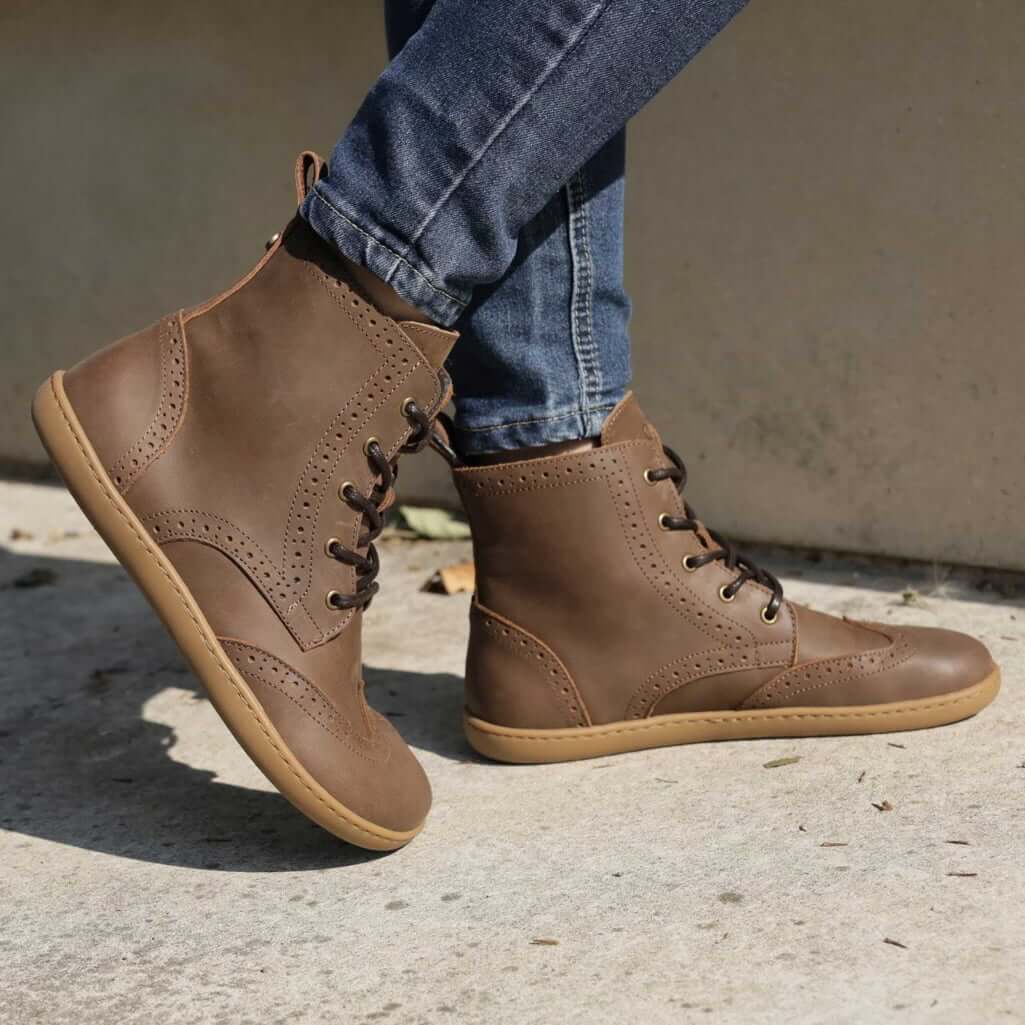 model wearing maple mid barefoot brogue boots in brown with blue jeans outdoors