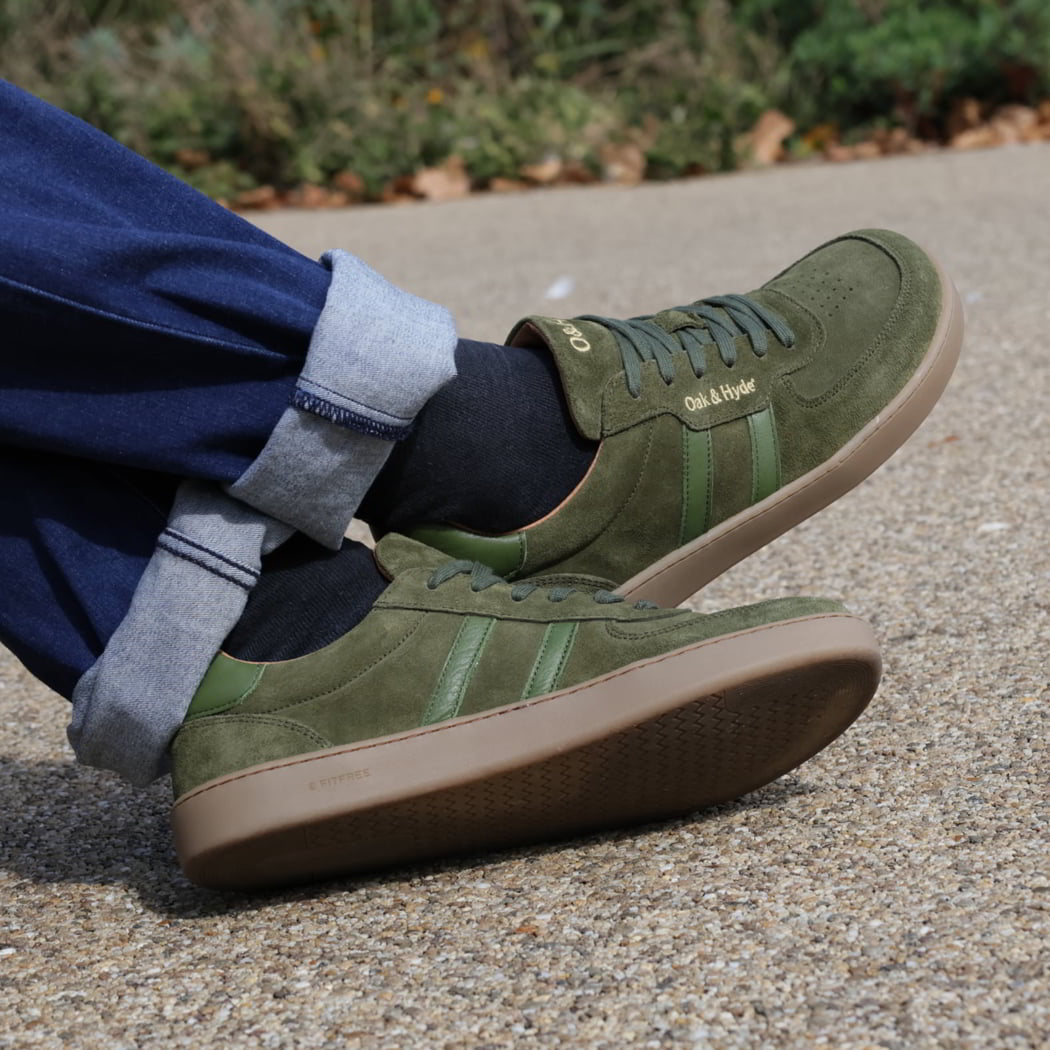 person wearing mens larch barefoot trainers in green sitting outdoors