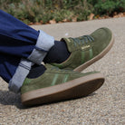 person wearing mens larch barefoot trainers in green sitting outdoors