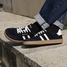 model sat on stone step wearing mens larch barefoot trainers in navy with blue jeans