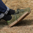 person wearing mens larch barefoot trainers in green sitting outdoors