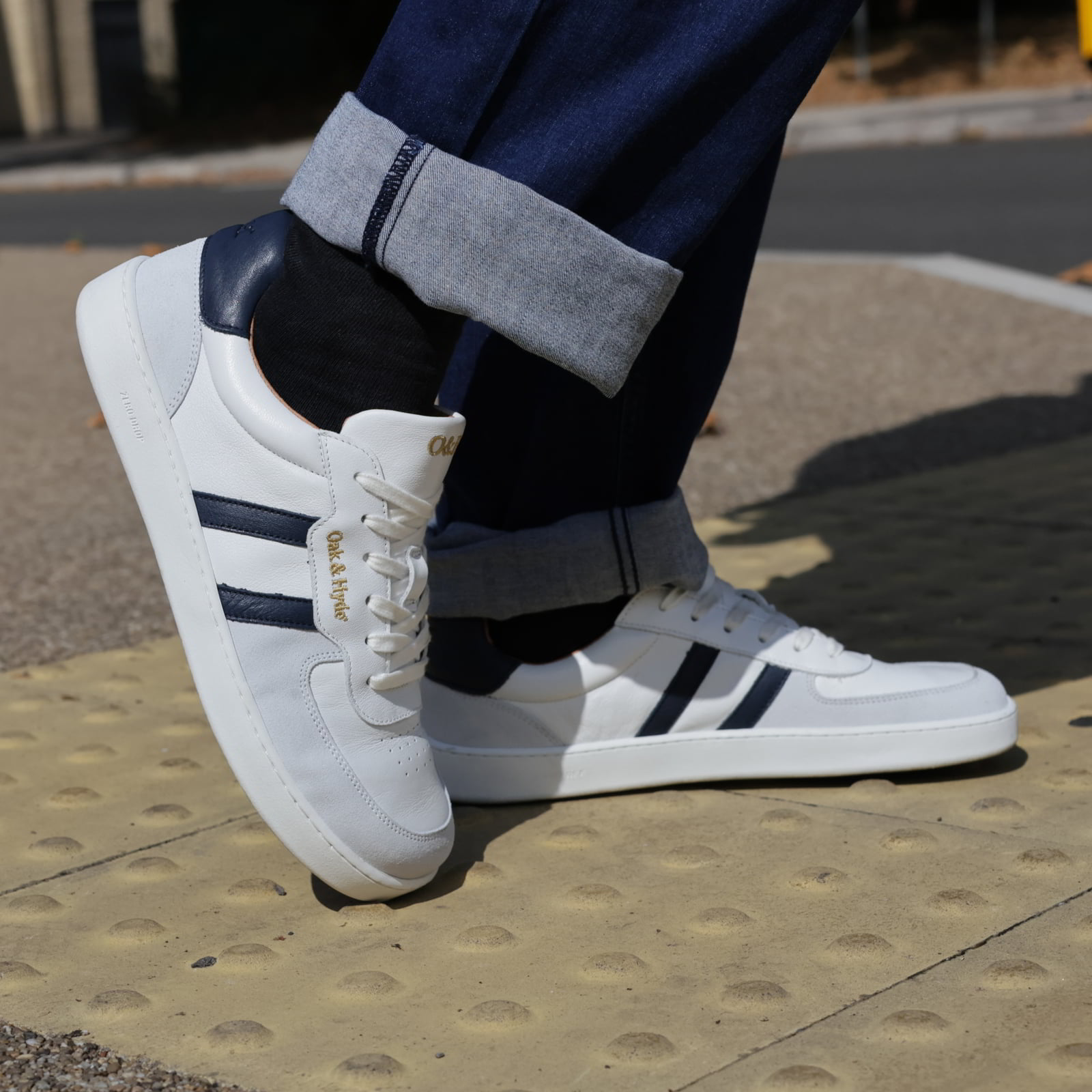 model standing outdoors wearing mens larch barefoot trainers in white navy