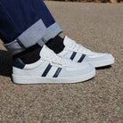 model wearing mens larch barefoot trainers in white navy with dark blue jeans