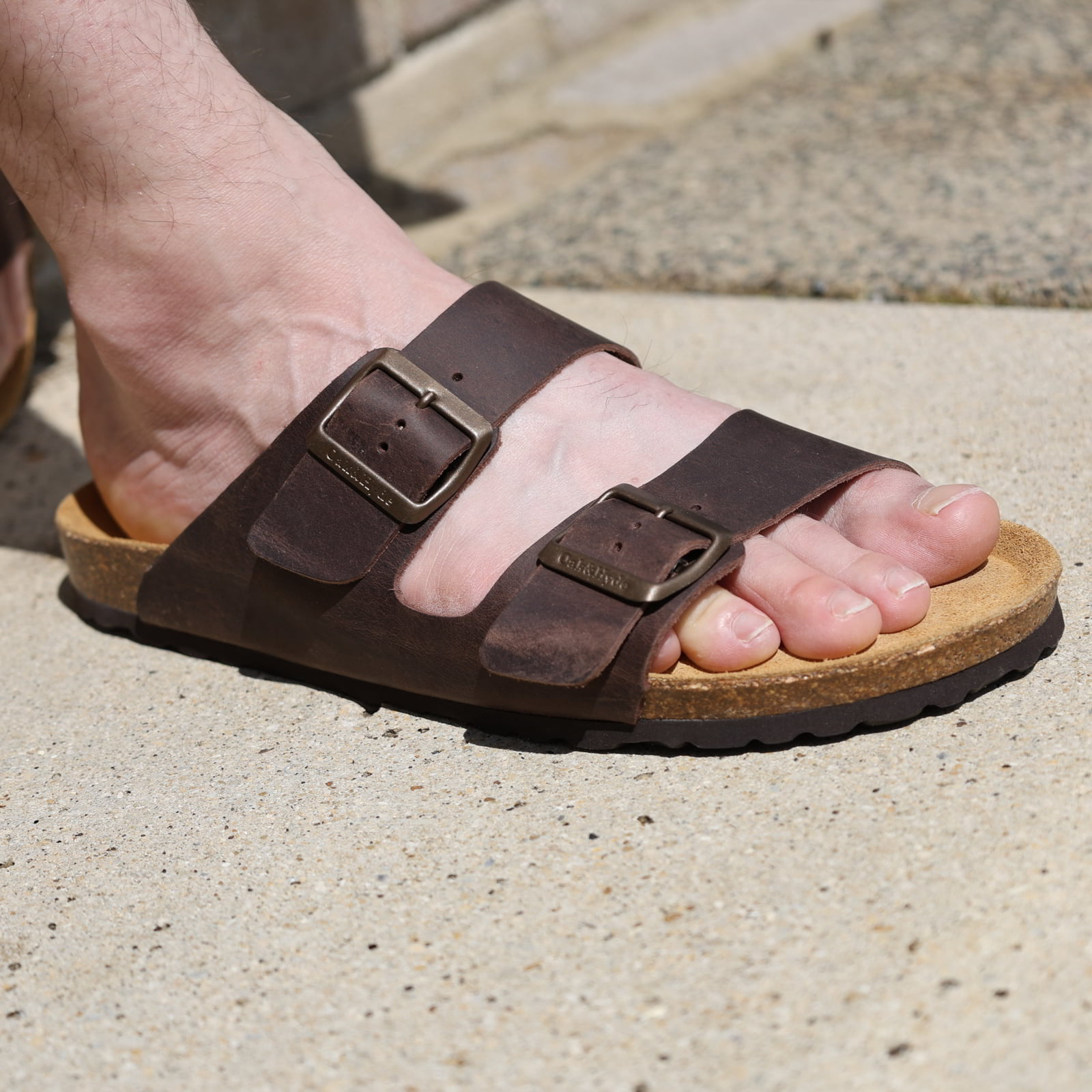 dark brown oak & hyde malaga sandals worn outdoors showing open toe straps and cork footbed