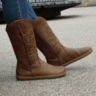 model outside wearing mesquite cognac barefoot cowboy boots sitting on a bench