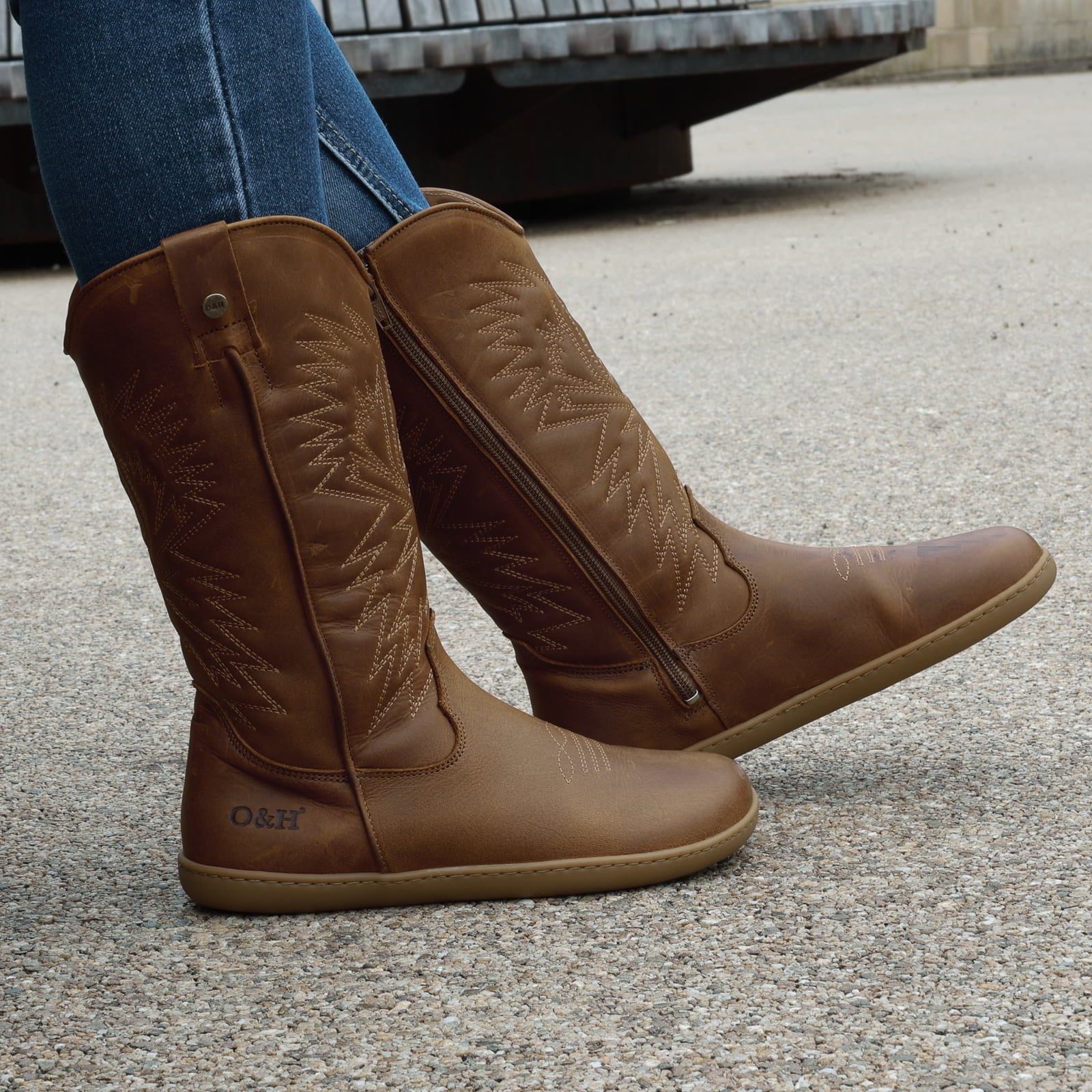 model outside wearing mesquite cognac barefoot cowboy boots sitting on a bench