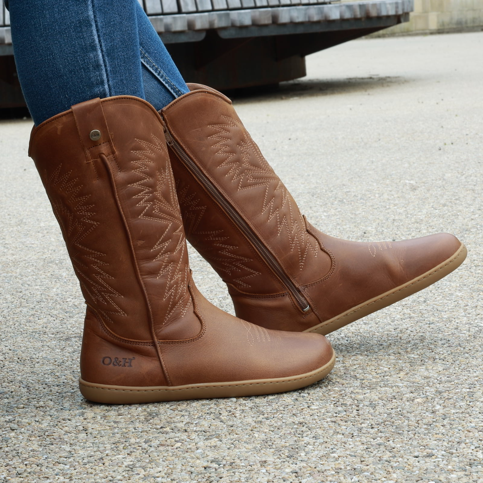 model outside wearing mesquite cognac barefoot cowboy boots sitting on a bench