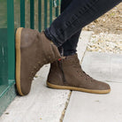 model leaning against metal container outdoors wearing mulberry barefoot ankle boots in brown