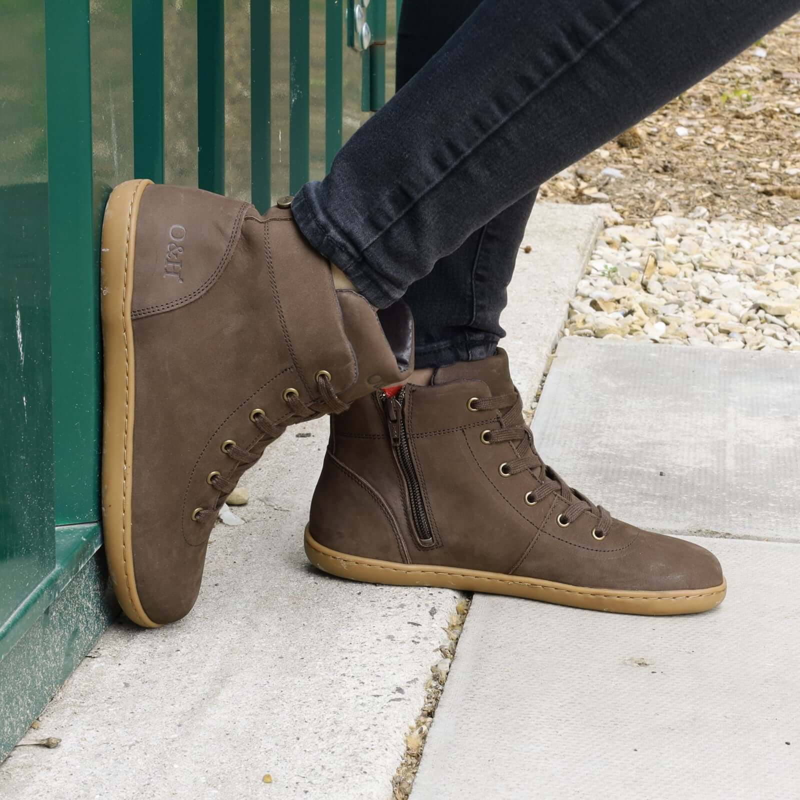 model leaning against metal container outdoors wearing mulberry barefoot ankle boots in brown