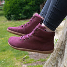 model sitting on tree trunk wearing mulberry barefoot ankle boots in wine with jeans