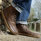 model standing in redwood barefoot boots in dark brown leaning against a wall